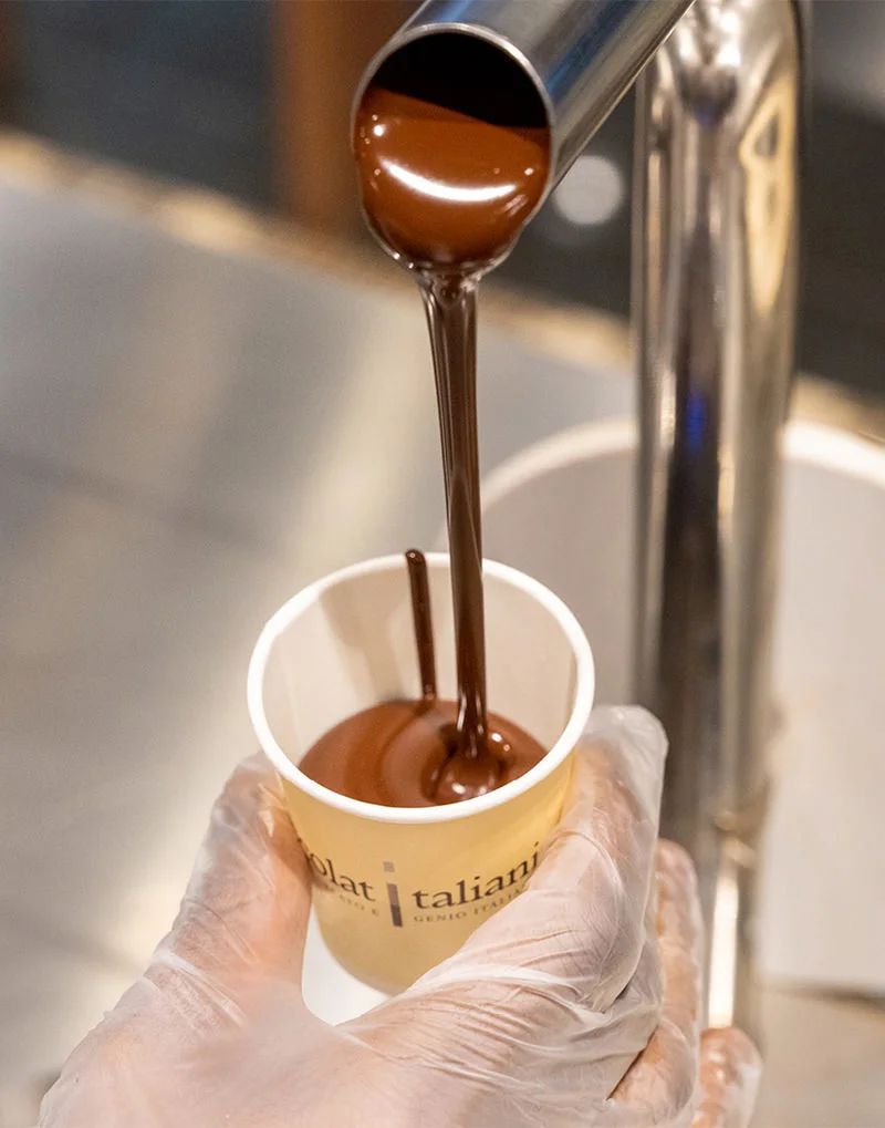 A tap is pouring liquid chocolate into a small cup at CioccolatItaliani